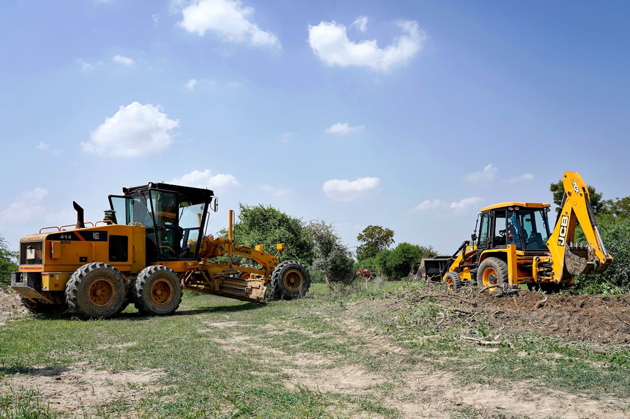 View of construction vehicles working in a lush field in Sanand, India.